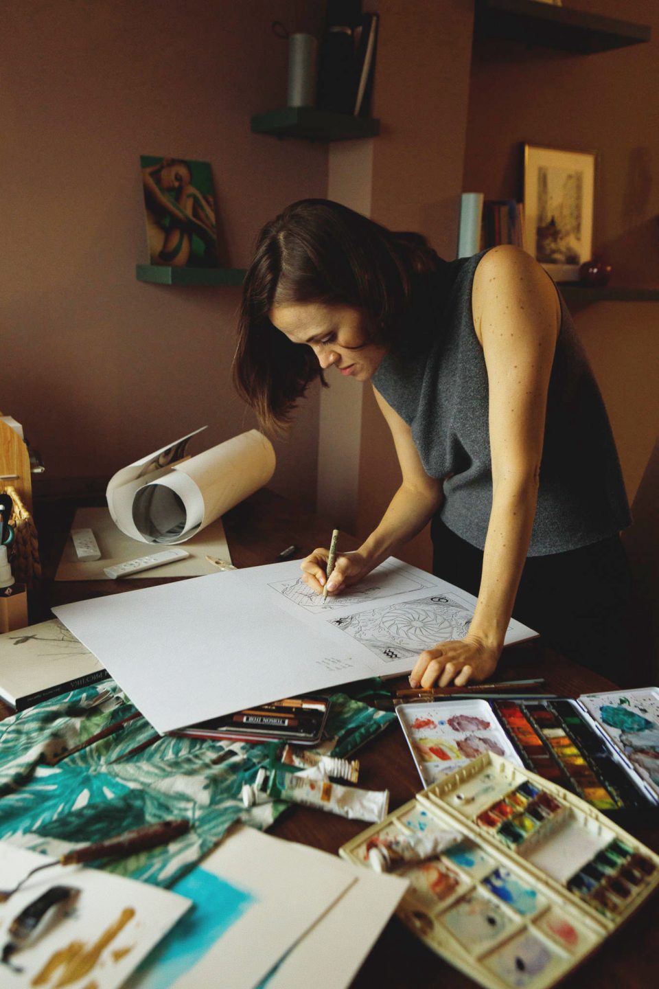 A designer painting watercolour prints at her desk