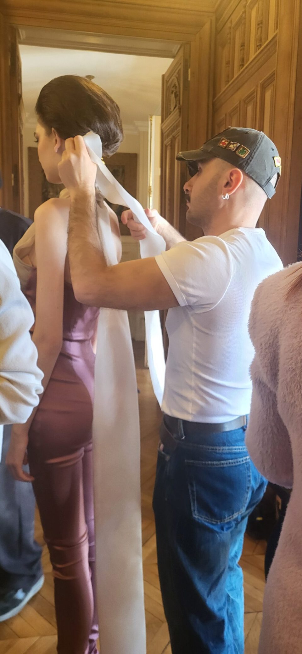 A tailor fitting a long gown on a model